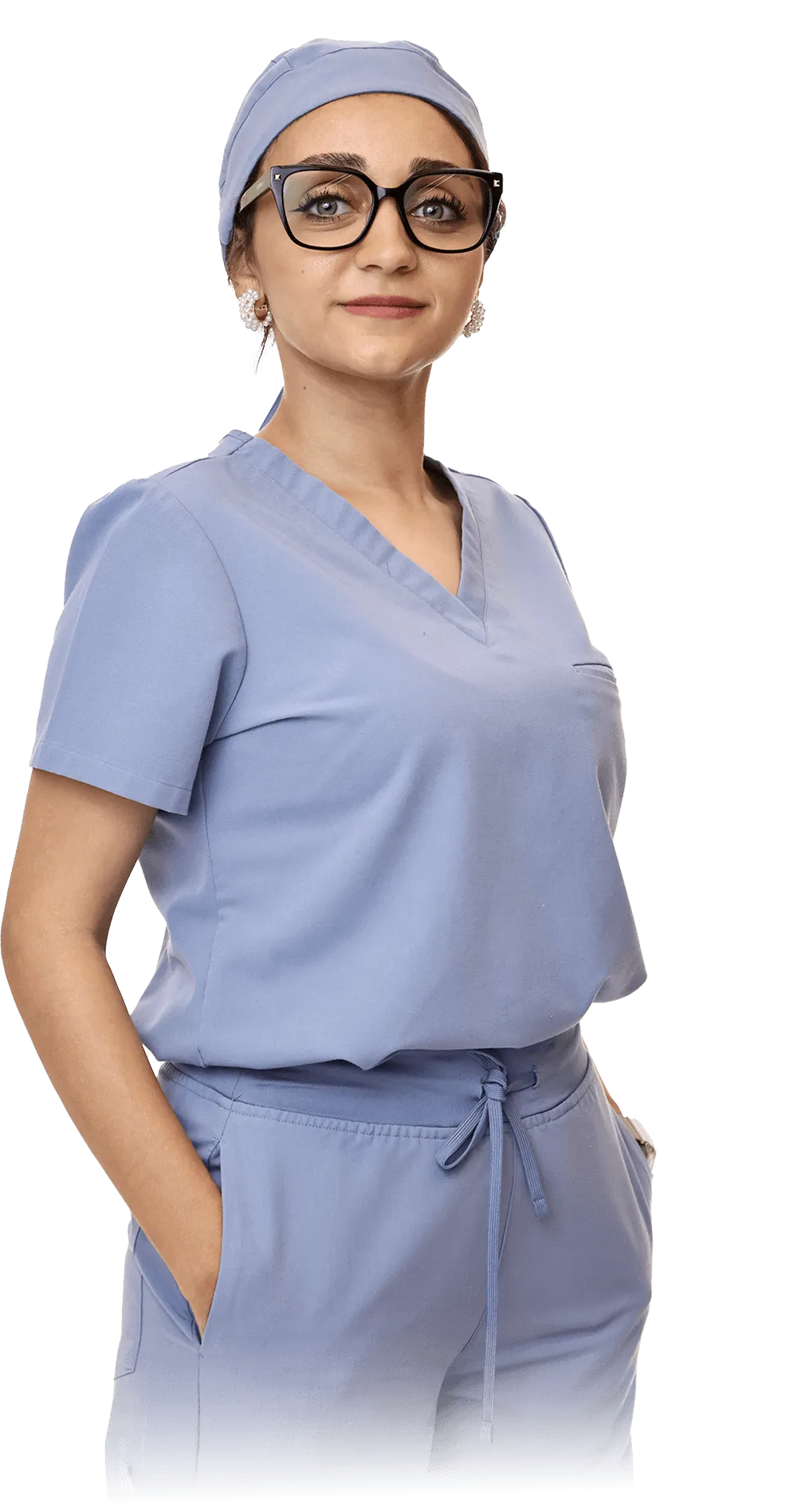 A female dental professional, Asma, in blue scrubs and matching headwear, confidently standing with her arms crossed. She wears glasses and has an approachable expression, ready to care for pediatric dental patients.