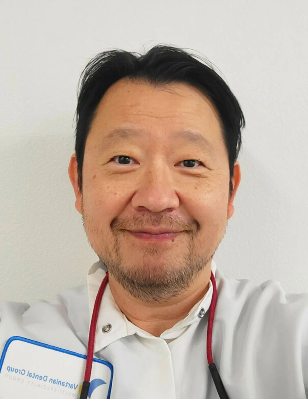 Dr. Park smiling for a portrait in a white lab coat with his practice's name badge visible, radiating a friendly demeanor.