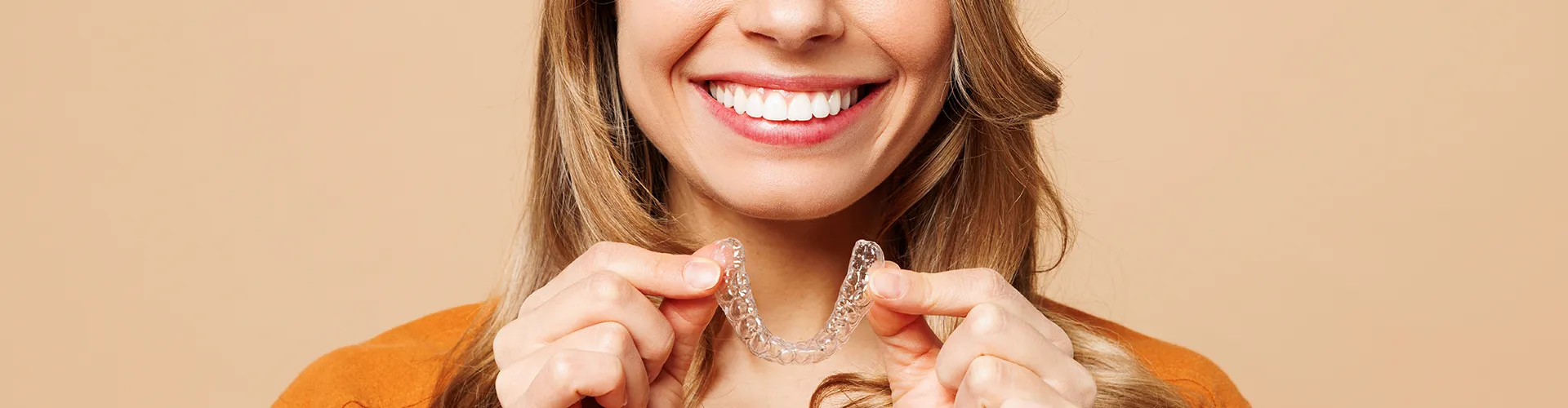 smiling woman holding clear aligner