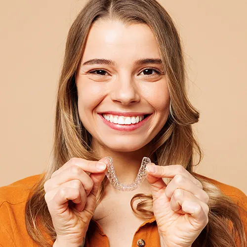 smiling woman holding clear aligner