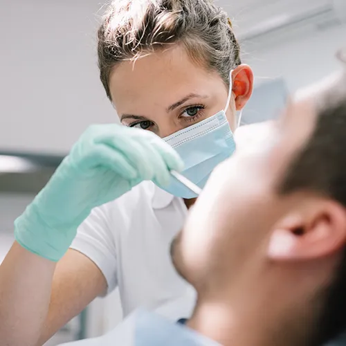 female dentist using dental tool in male patient's mouth