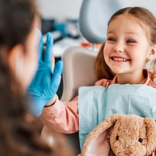 smiling child holding bunny looking at dentist